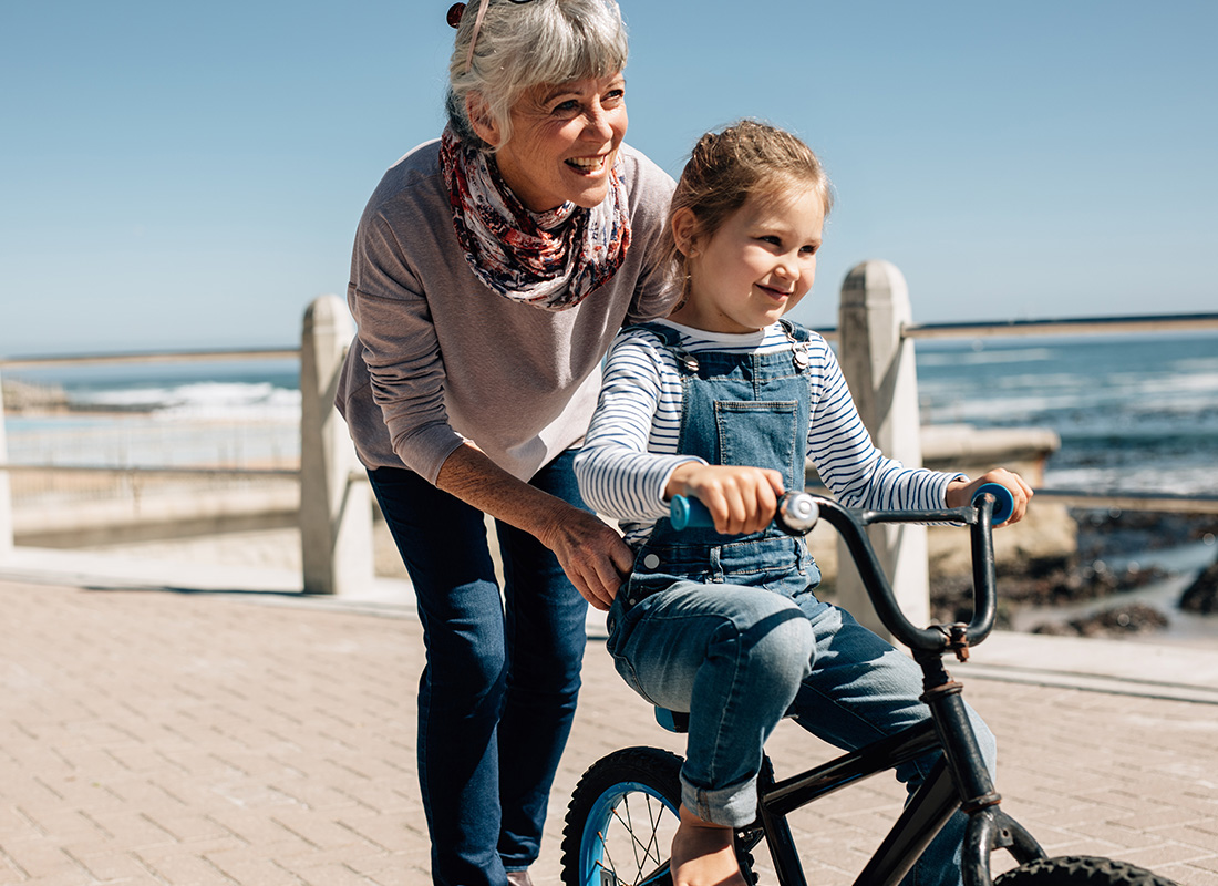 About Our Agency - Grandmother Teaching Her Granddaughter to Ride a Bike